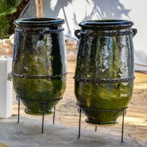 Dos jarrones altos de cerámica barnizada verde sobre soportes metálicos.